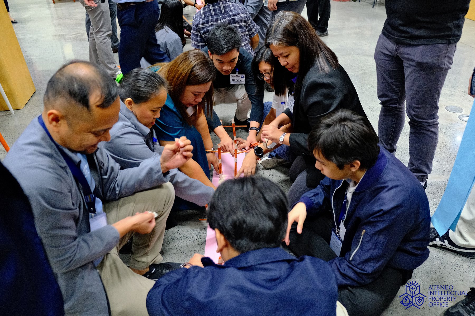 Participants building a structure together on the floor during the on-site workshop